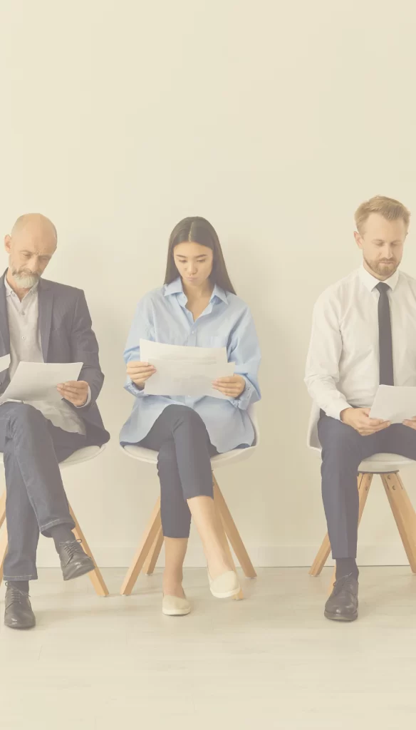 New interviewees studying paperwork while waiting outside of an interview room.